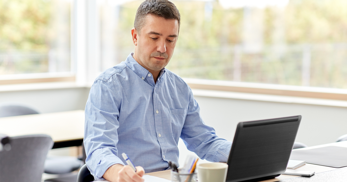 middle-aged man with calculator, papers and laptop computer working in office