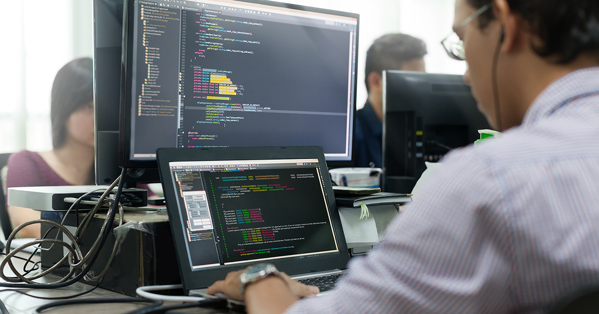 Developer Looking at Screen Sitting at Desk Working on Desktop Computer