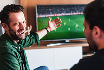 two men watching a sporting event on tv