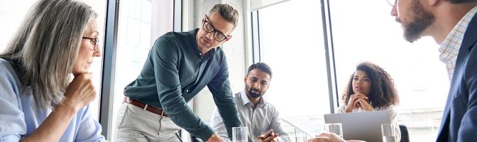 Male mature ceo businessman leader with diverse coworkers team working together on project in boardroom
