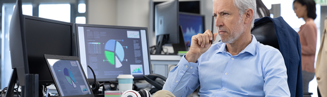 businessman working in a modern office, sitting at desk using computers, thinking.