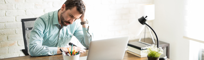 Frustrated business owner sitting with a hand on his head and a worried look