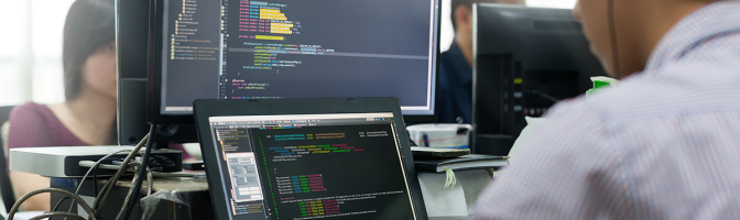 Developer Looking at Screen Sitting at Desk Working on Desktop Computer