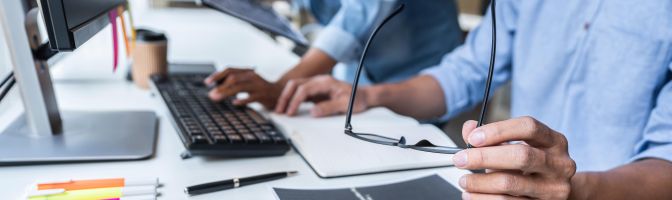 Two people sitting at a desk in front of a lap top.