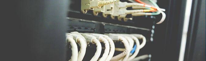 Image of fiber and Ethernet routers mounted on a rack in a cabinet