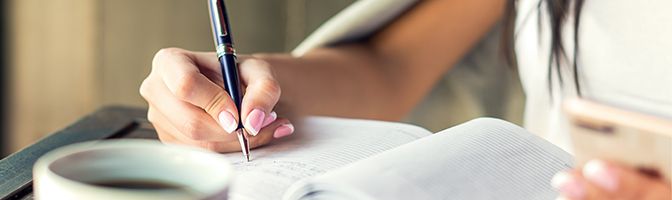 Businesswoman writing in a notebook with a pen.