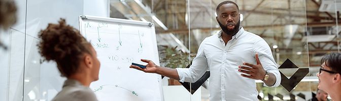 Small business owner stands while giving a presentation to their staff members.