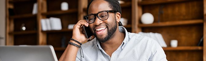 A successful and confident entrepreneur is smiling as he speaks to someone on a mobile phone.