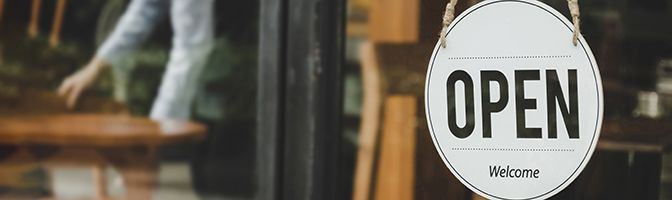 Closeup of an "Open" sign hanging in the window of a business.