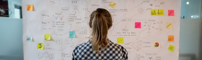 woman looking at board with post it notes