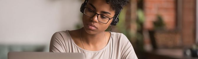 woman using laptop while wearing headphones