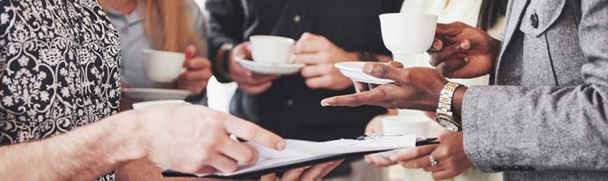 closeup of a stand up meeting with people looking at a tablet