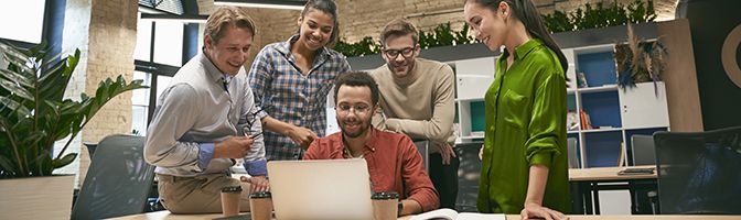 Group of business professionals around a laptop watching a video.