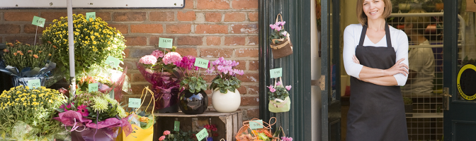 Female flower gift shop owner standing at store front entrance