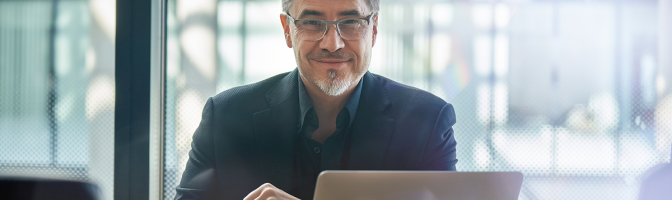Mature businessman sitting in in office working with laptop computer.
