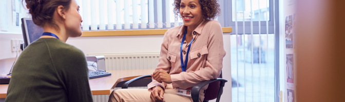 Female business manager having a conversation with female employee sitting down in office