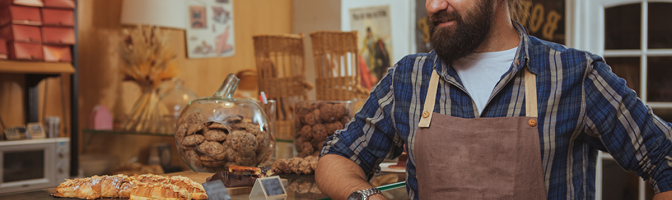 Bearded baker enjoying working at his own bakery shop.