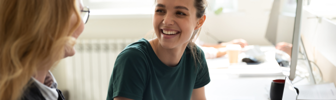 Happy smiling female trainee discussing business ideas with adult trainer