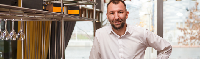 Cheerful friendly male waiter welcoming you at the restaurant