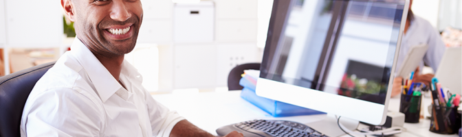 Businessman At Computer In Office smiling