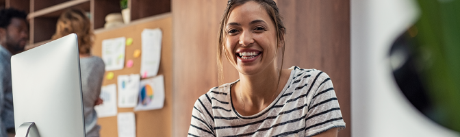 Portrait of smiling young business woman sitting at her desk in an office.