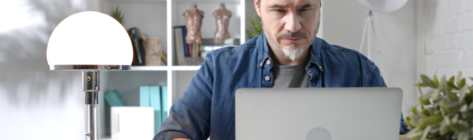 Man in casual sitting at desk using laptop computer, business manager online in home office.