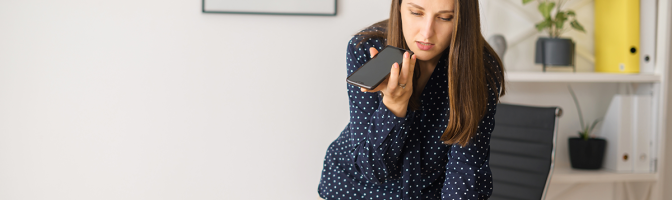Busy female employee is using voice assistant on the smartphone
