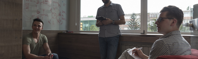 small group of three employees in private office have team meeting and brainstorming while working on laptop and tablet computer