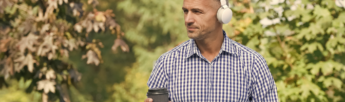 gentleman sitting outside listening to podcast while drink coffee