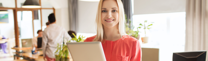 happy businesswoman in office with tablet