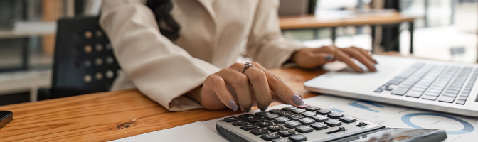 Close-up of businesswoman hands using a calculator to check company finances and earnings and budget