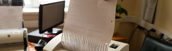 a man destroys paper documents in a shredder.