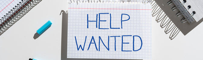 A piece of notebook paper with "Help Wanted" written on it. 