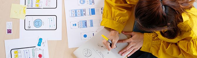 Overhead view of a woman making revisions to designs of a product.