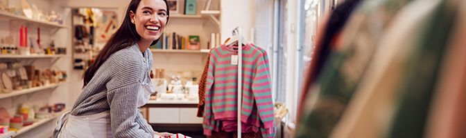 Business owner preparing clothing store for customers.