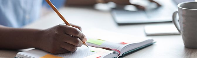 A business professional writing notes in a journal.