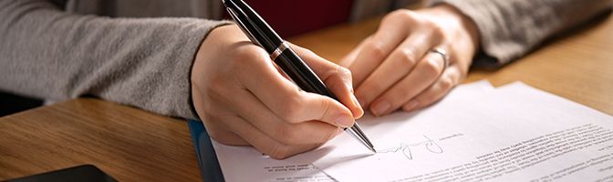 Closeup of the hands of a business person holding a pen while reviewing a document.