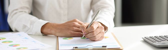 A small business owner looks over financial information while sitting at their desk.