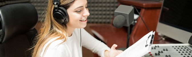 Woman with clipboard in hand sitting in soundproof room at radio station and hosting a talk show live