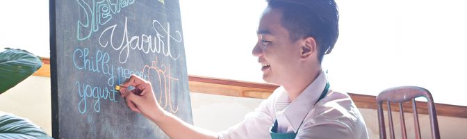 Cafe owner writing special menu on the chalkboard