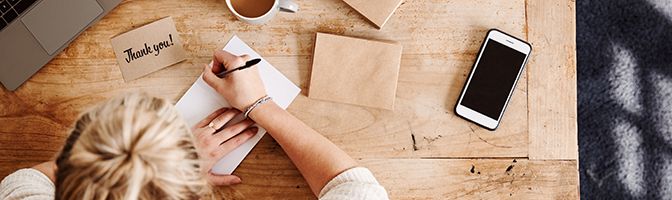 Business owner writing thank you cards to employees.