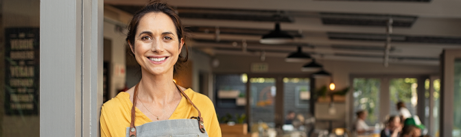 Female small business owner smiling in front of store.