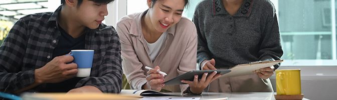 Three people looking at a tablet screen.