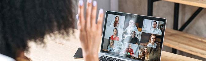 Small Business owner waves in a video conference call with staff.