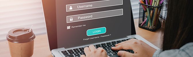 A small business owner typing in a username and password at a laptop.