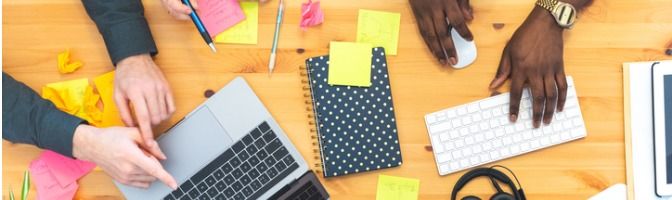 Employees in a small office brainstorm ideas in front of a laptop