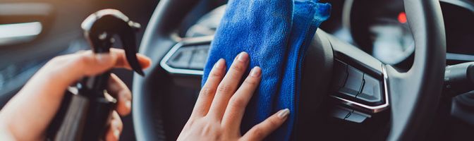 close up of someone cleaning their steering wheel with a blue rag