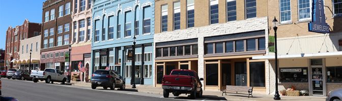 cars parked on rural downtown street in front of older 3-story buildings