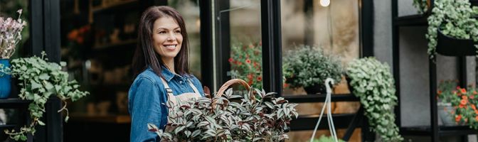 Small business owner with fresh flowers and sale in front of store.