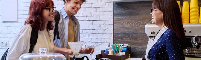 Customers of coffee shop making an order, talking to female barista cafe worker